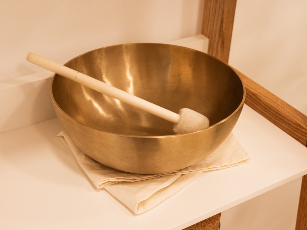 Klangschale mit Klöppel auf einem Kissen -- Sinnbild für die Klangtherapie